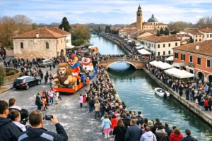 Veduta aerea panoramica del Carnevale dei Storti a Dolo, con la folla e i carri allegorici che colorano le vie del centro e le rive del Naviglio del Brenta.