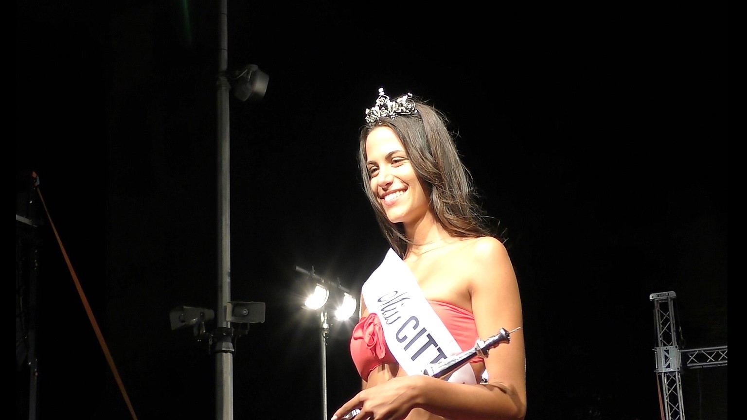 Nella foto Nicole Cogo con la fascia di Miss Città Murata 2017, la corona e uno scettro che sorride verso i fotografi.
