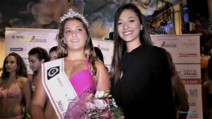 Giulia Monaco posa sorridente mentre riceve la fascia ufficiale di Miss GidiferroTeam, affiancata da Giada Casellato, collaboratrice del team, durante le premiazioni della serata Miss Blumare.