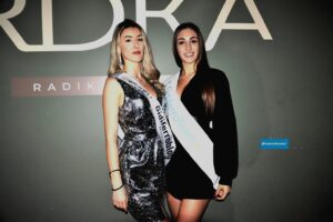 MariaSole De Vito sorride mentre riceve la fascia di "Miss Gidiferroblog" da Giulia Urbinati, che ha partecipato alla serata in veste di premiatrice al Radika di Treviso.
