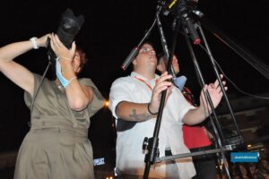 Uno scatto del dietro le quinte di Miss Venice Beach che ritrae tre membri dello staff tecnico all'opera: due fotografi concentrati sulla scena e il videomaker Andrea Bonesi di GidiferroTeam con la sua attrezzatura, pronti a catturare ogni momento della serata.