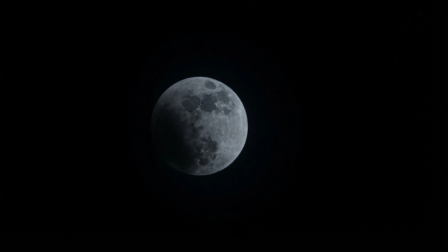 Immagine della Luna nella fase intermedia dell’eclissi parziale del 28 agosto 2026, con una copertura di circa il 50%. La metà sinistra del disco è oscurata dall’ombra terrestre, mentre la parte destra rimane luminosa e ben definita. Sono visibili contrasti marcati tra le zone illuminate e quelle in ombra. Il cielo è nero e privo di nuvole. L’immagine documenta la progressione dell’ombra terrestre sul disco lunare.