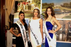 Fotografia che ritrae le prime tre classificate della finale di Miss Riviera del Brenta 2026. Al centro Sofiabeatriz Rizzioli, vincitrice, con fascia Miss Riviera del Brenta 2026 e corona, in abito bianco. Alla sua sinistra Elisa Carestiato, con fascia Miss Eleganza 2026, in abito nero con dettagli piumati. Alla sua destra Gioia Cavallari, con fascia Miss Serenissima 2026, in abito blu. Le tre finaliste posano davanti a un pannello con immagini della Riviera del Brenta, tra cui una peata storica, ville venete e ambienti eleganti. L’atmosfera è formale e celebrativa.