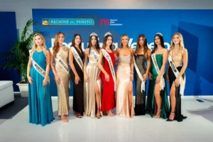 Foto di nove Miss schierate in abito da sera, ciascuna con fascia identificativa e alcune con corona. Le partecipanti posano davanti al fondale blu con i loghi “Regione del Veneto” e “Veneto Film Commission”. Le fasce riportano titoli diversi legati a sponsor e località. L’immagine rappresenta la componente elegante e rappresentativa del progetto Miss Città Murata durante l’evento ufficiale.
