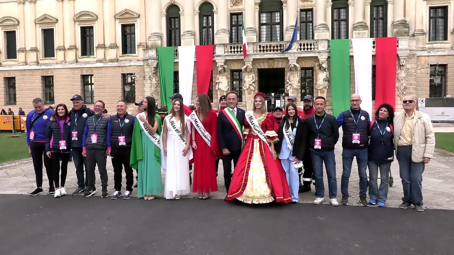 Foto di gruppo ufficiale all'aperto davanti al monumentale ingresso di Villa Pisani. Sindaci, autorità locali con la fascia tricolore, organizzatori dell'evento e le Miss con le fasce e gli abiti di rappresentanza posano sorridenti in fila per una foto ricordo, con festoni tricolori appesi ai balconi del palazzo.